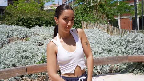 a woman in a tank top sitting on a bench in the city