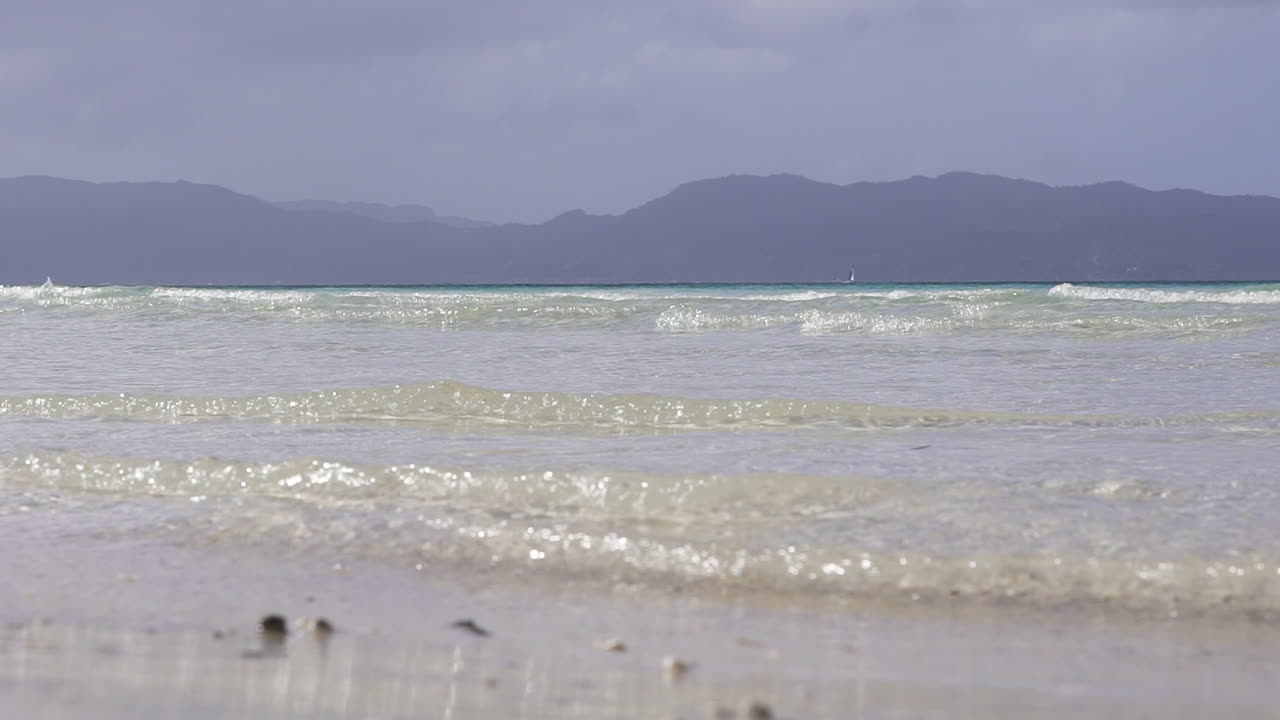 아름다운 하얀 해변의 해안을 때리는 작은 파도의 슬로우 모션 롱샷