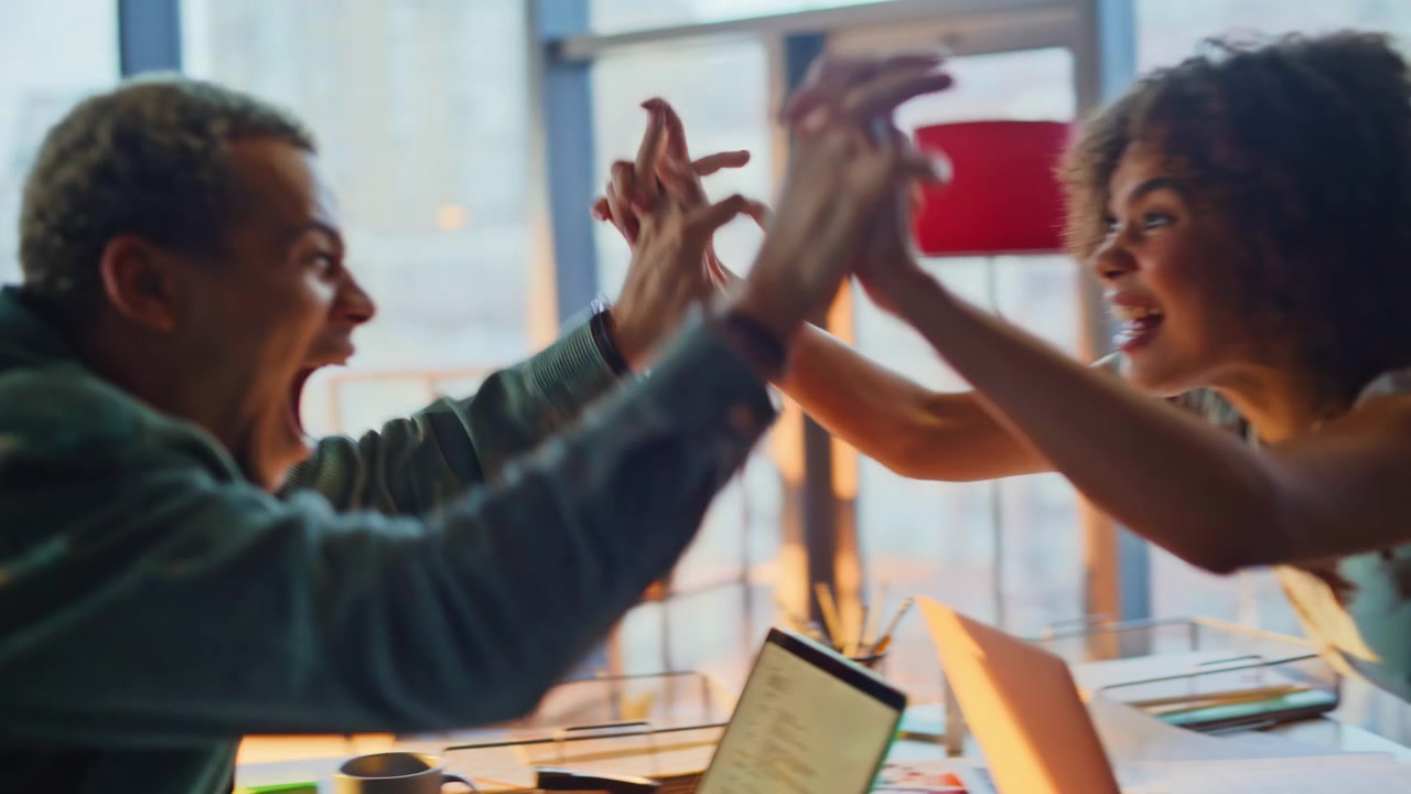 Excited man getting good news phone call office. Coworkers high five celebrating