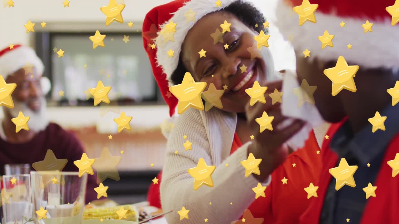 Animation of stars over african american family wearing santa claus hats