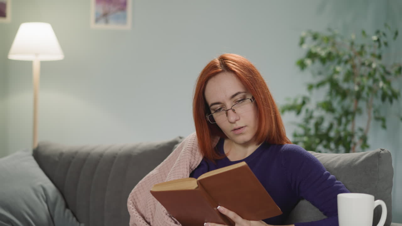 Femme rousse à lunettes apprécie la lecture d'une histoire d'amour captivante