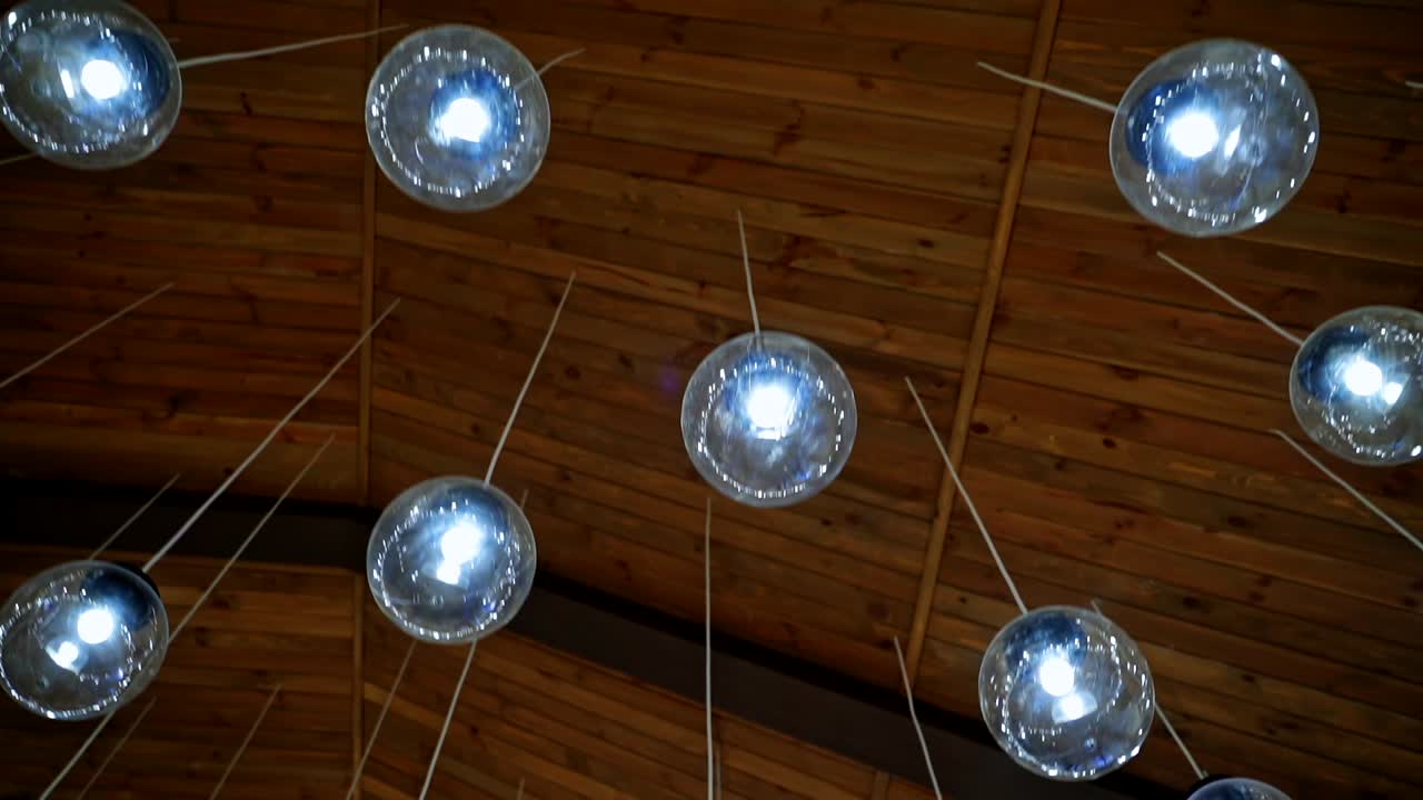 Modern ceiling lighting. Brown background with beautiful round glass ball lamps hanging on white wires. Luxury design of the room.