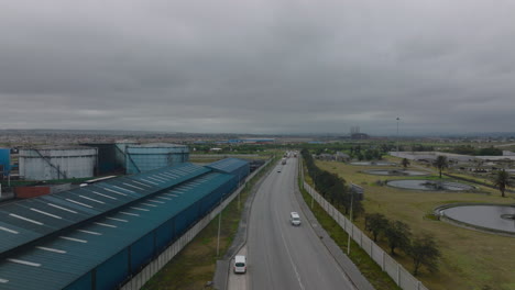 Forwards-fly-above-road-loading-in-industrial-suburb-on-cloudy-day.-Large-cylindrical-tanks-for-materials-in-factory.-Port-Elisabeth,-South-Africa