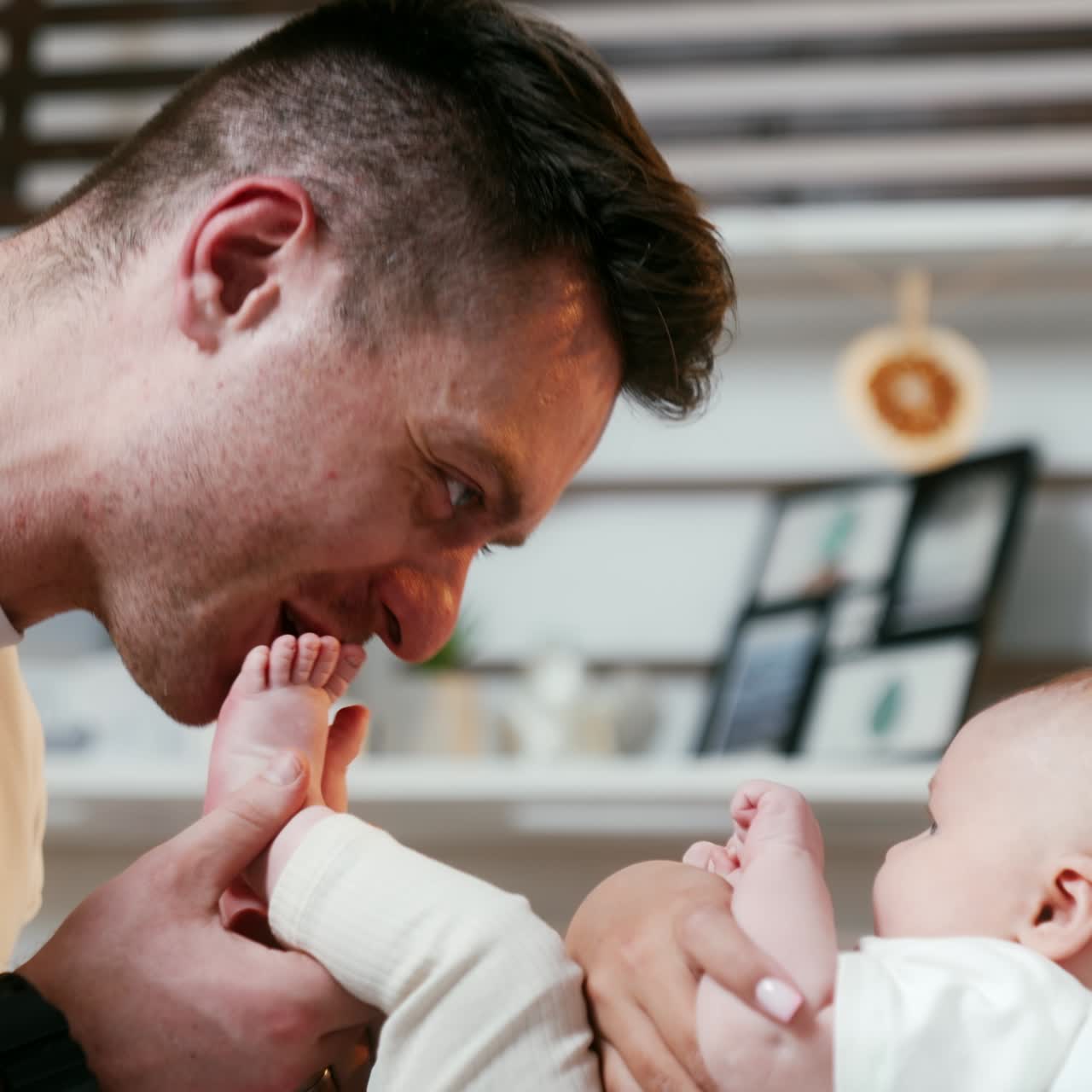 Happy smiling couple holding their newborn. Father is kissing tiny baby feet. Close up