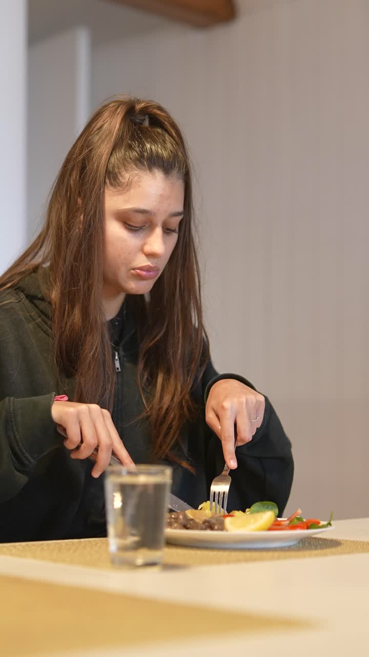 una adolescente comiendo la cena.