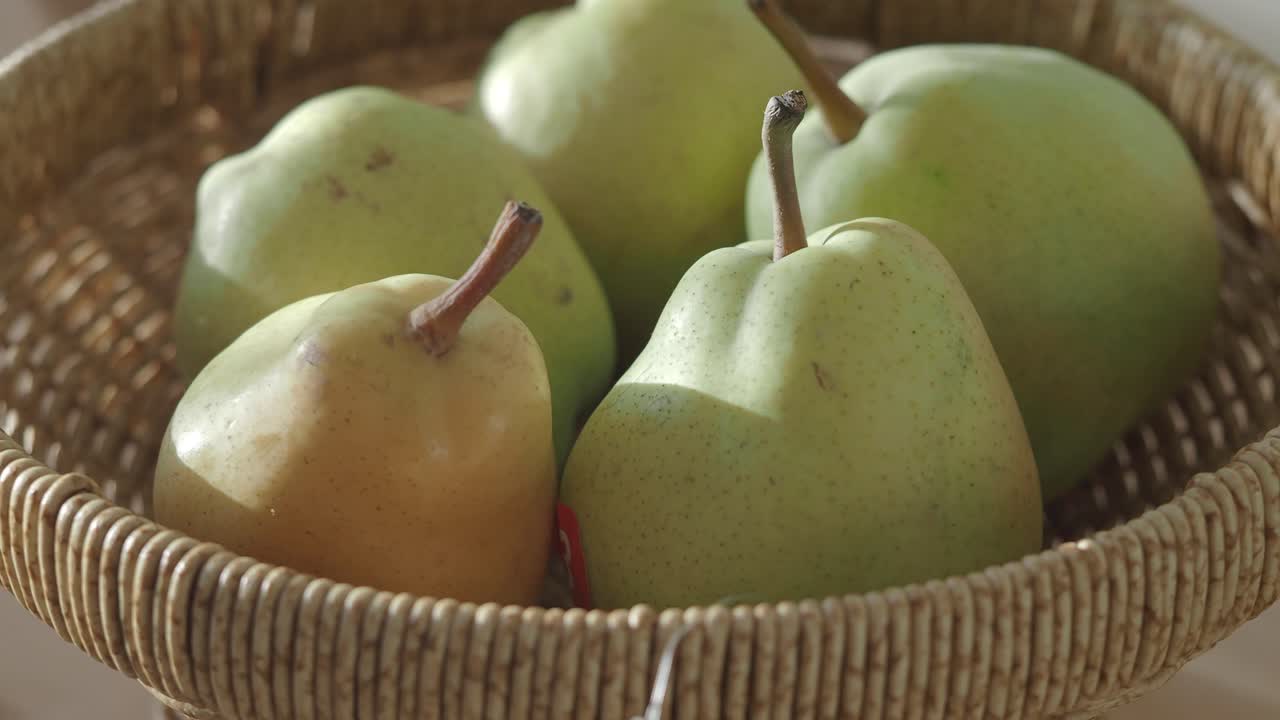 Pere verdi fresche in un cesto intrecciato
