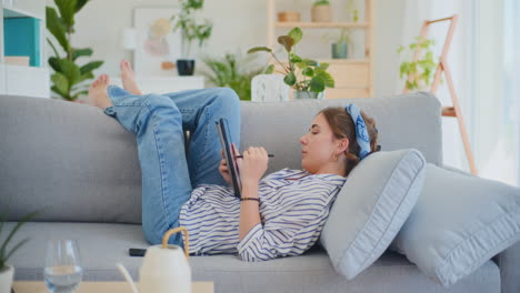 mujer feliz disfrutando de las redes sociales en el sofá con una tableta digital