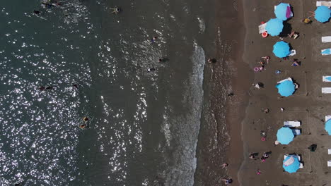 aerial view still image of people sunbathing on the beach and swimming in the sea, sunbeds and umbrellas on the beach