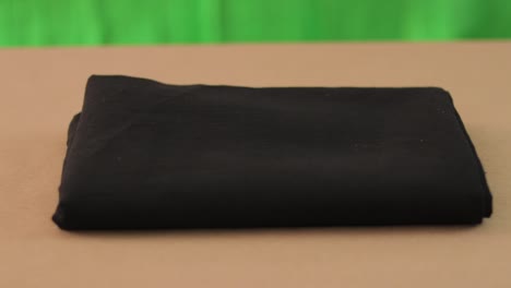 black fabric on a brown surface and green background