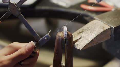 caucasian female worker shaping jewellery with saw in studio in slow motion