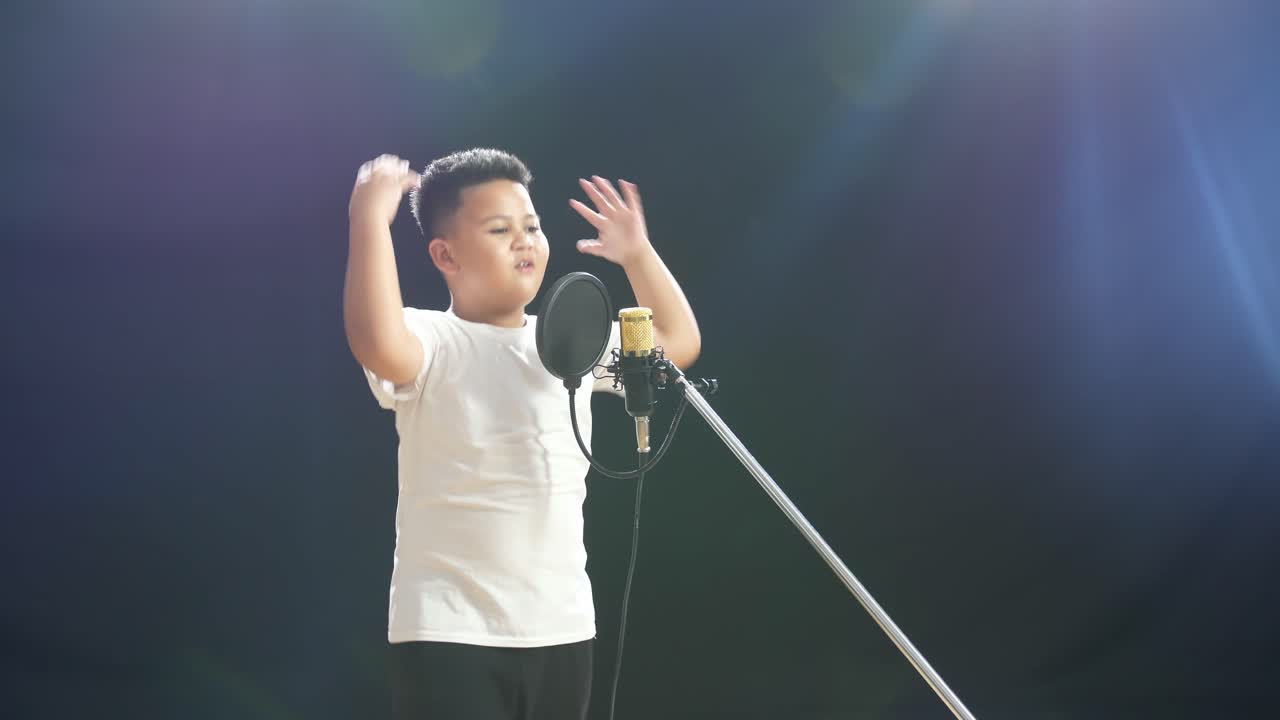어린 소년 이 마이크 로 노래 하고 있다