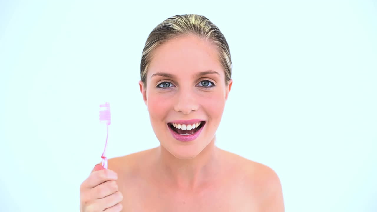 una mujer rubia cepillándose los dientes.
