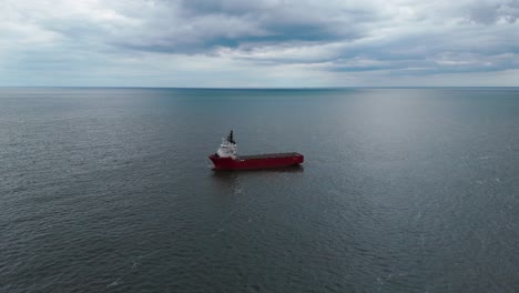 aerial view of the sea and a red cargo ship, rotating around it,uk