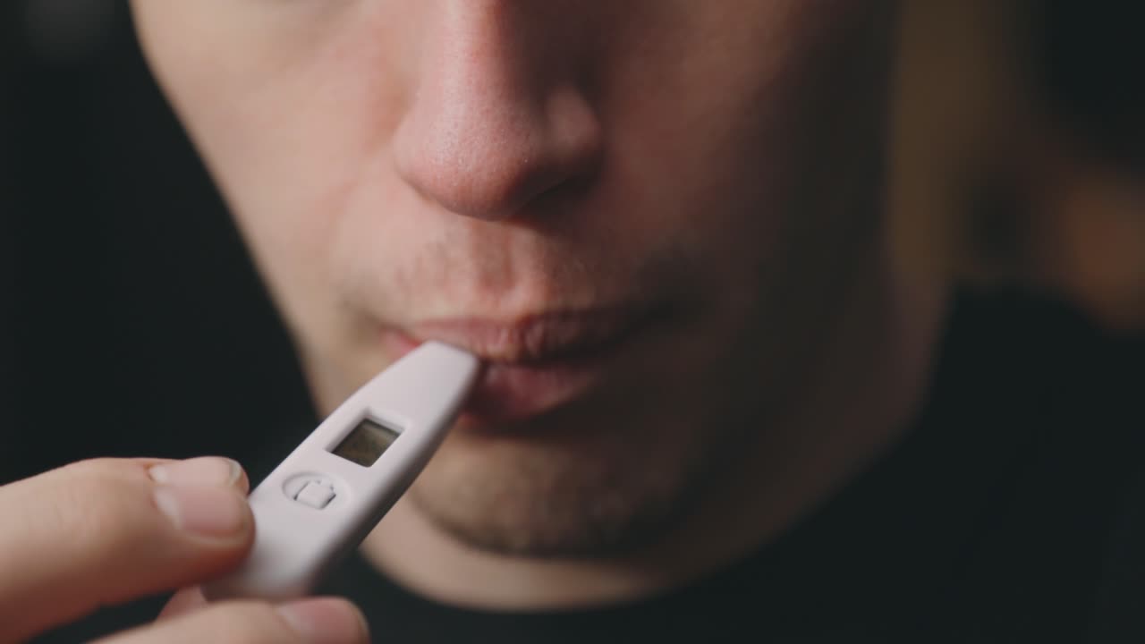 Uomo caucasico che misura la temperatura corporea