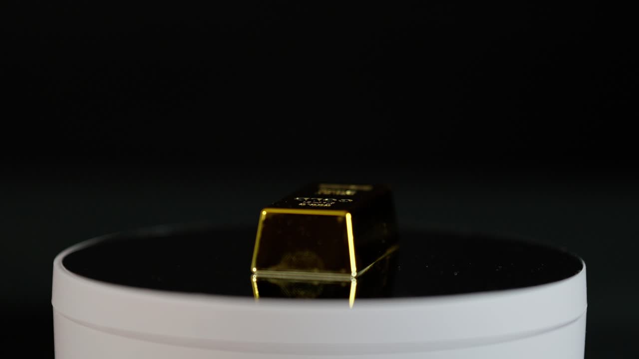 una barra de oro girando en una mesa giratoria de espejo, que simboliza la riqueza y el lujo