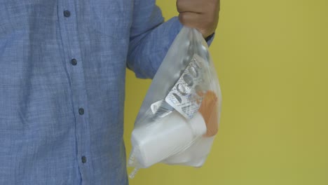 a person holds a plastic bag filled with pills and a white bottle.