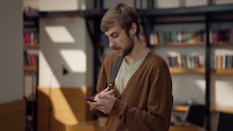 young man using smartphone in a library/cafe