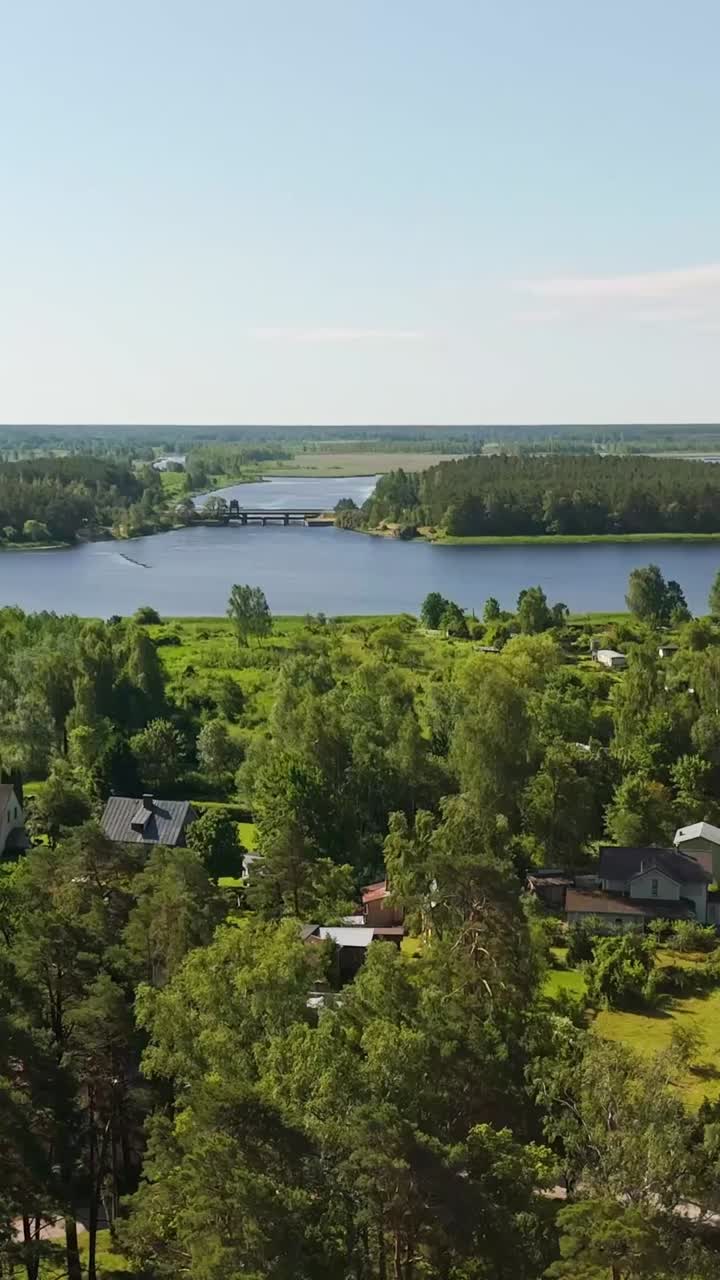 Aerial view of Lielupe river in Jurmala surrounded by forest, small town, vertical