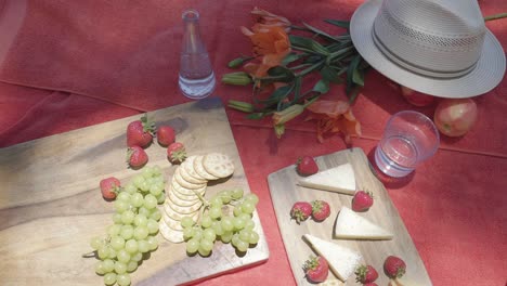 top down of vegetarian appetiser vegan cheese and fruit strawberry grape fruit on red tablecloth outdoor picnic concept