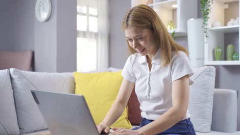 La-Joven-Que-Trabaja-Con-Una-Computadora-Portátil-En-Casa-Se-Regocija.