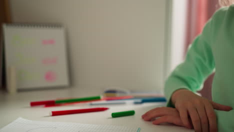 schoolgirl removes green cap from red felt-tip pen sharply