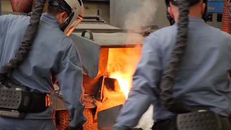 workers collaborating to melt metal at very high temperature