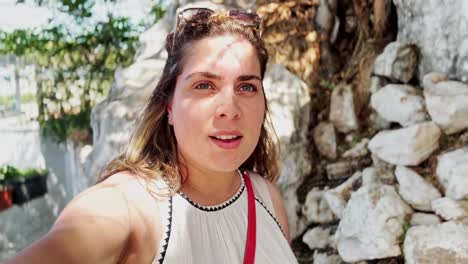 young woman vlogging her walk through a sunny alley