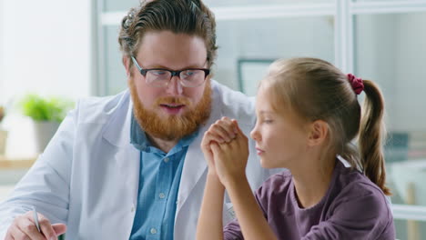 male pediatrician speaking with little girl in medical office