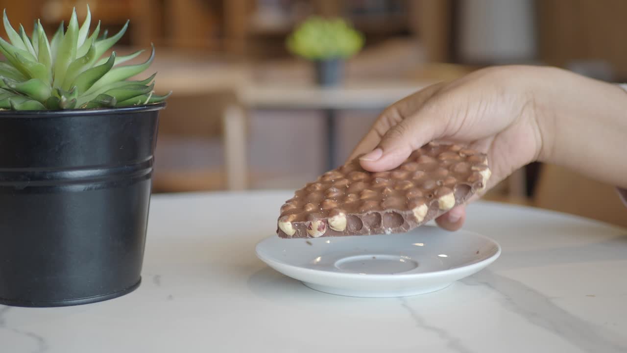 Person eating chocolate hazelnut bar in a cafe