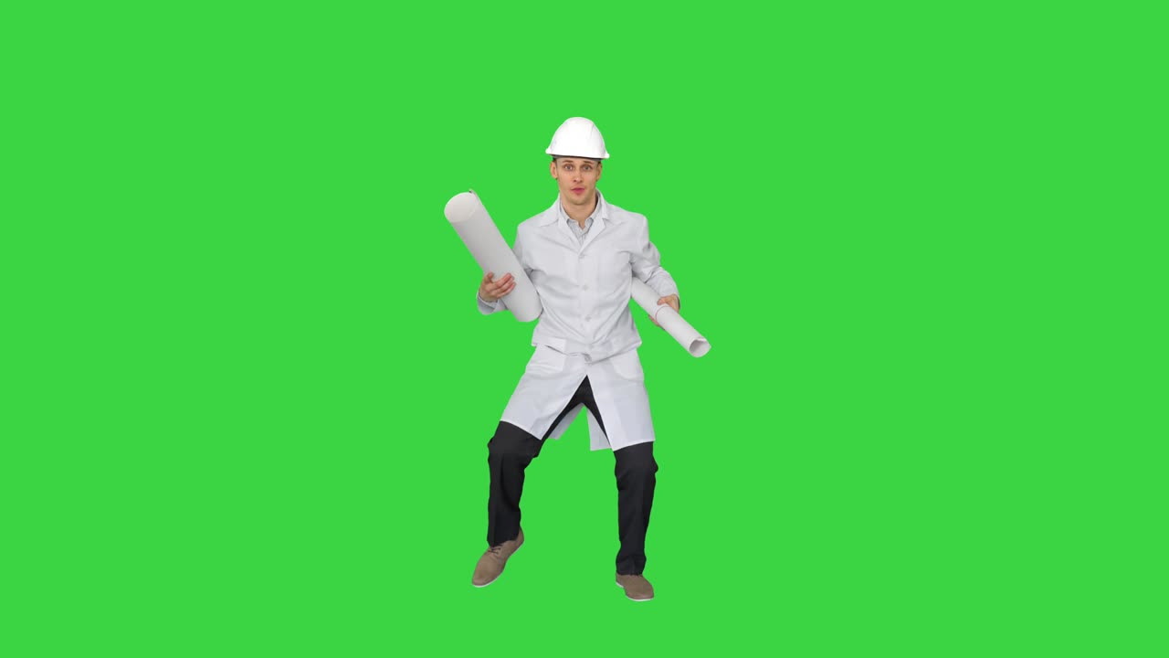 feliz joven ingeniero baila con planos de una manera divertida en una pantalla verde, clave de croma