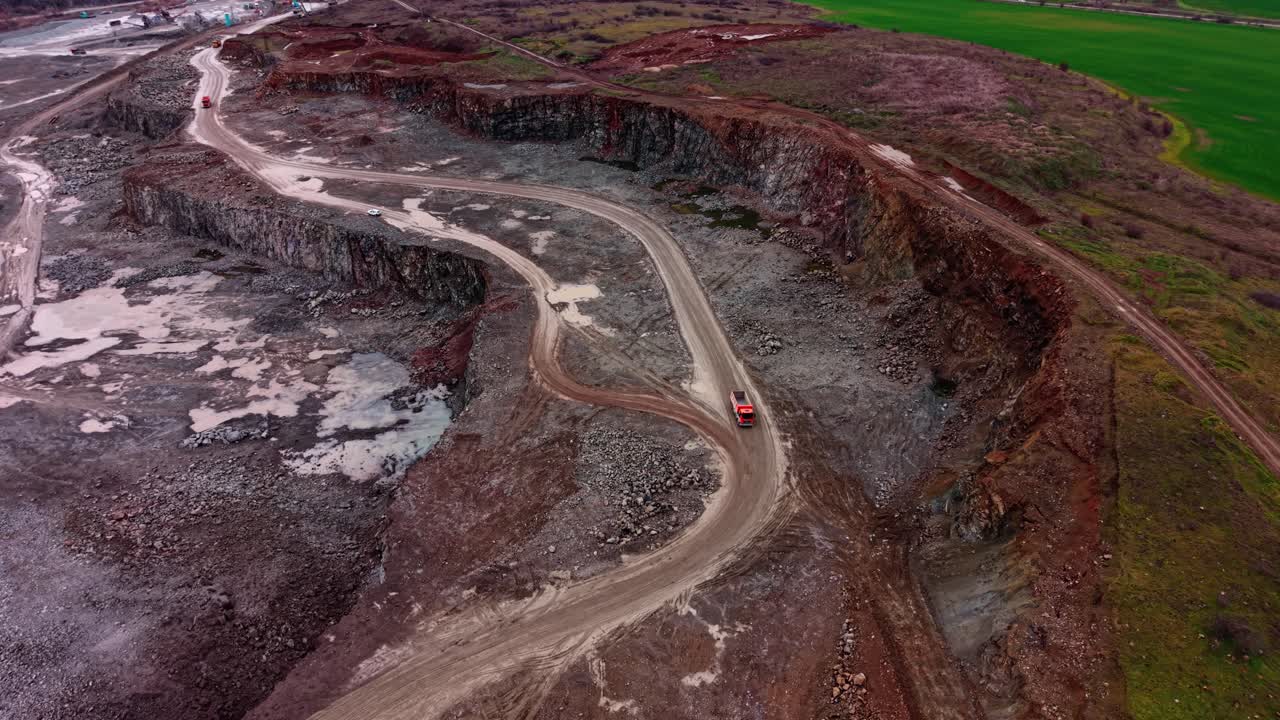 Granite quarry shows heavy machinery and vehicles on rough terrain