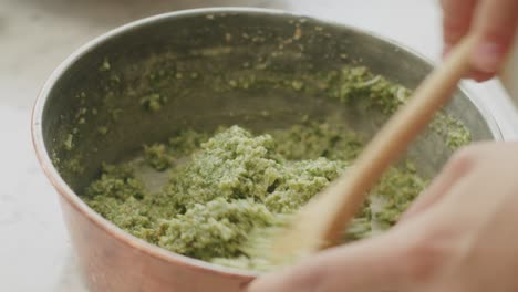 mujer de la cosecha mezclando salsa de pesto en el cuenco