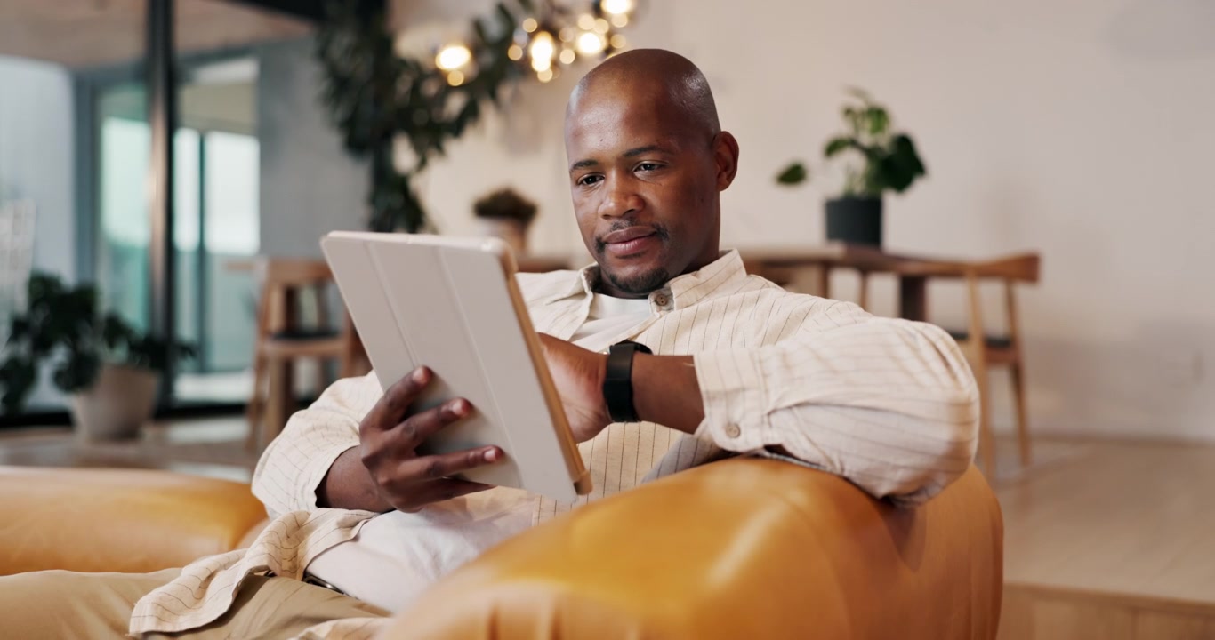 Man Relaxing on Sofa and Using Tablet in Modern Living Room