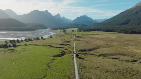 Aerial-view-of-rolling-green-plateau-and-remote-empty-road-in-the-mountainous-wilderness-in-Glenorchy,-South-Island-of-New-Zealand-Aotearoa