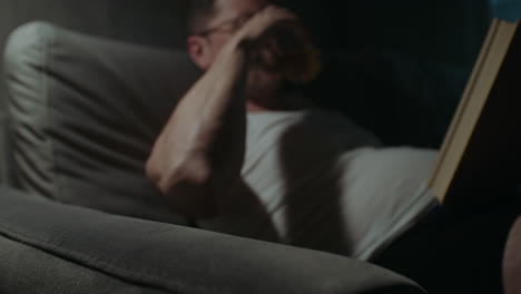 a sad man reads a book at night in his underwear