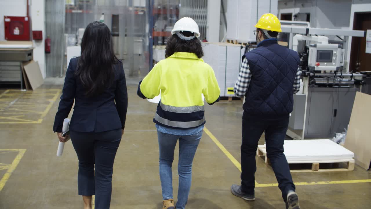 Vista trasera de trabajadores de fábrica caminando en la planta