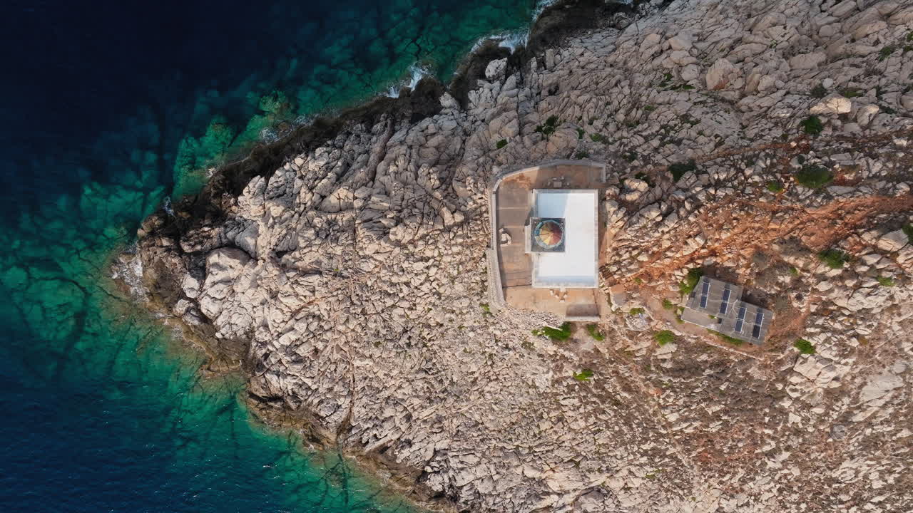Aerial high angle of Cape Tainaron cliff and white lighthouse beside rocky shoreline and sea