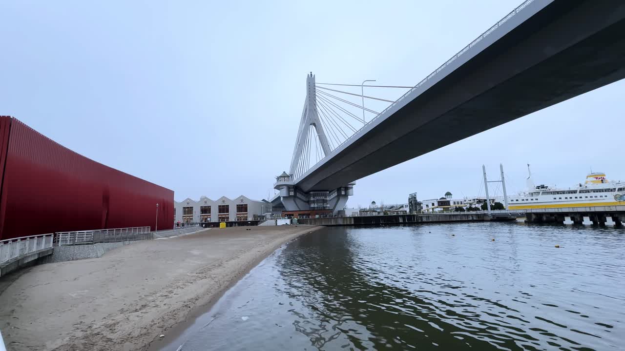 Modern cable-stayed bridge spans Aomori Bay with beach, water, and urban buildings