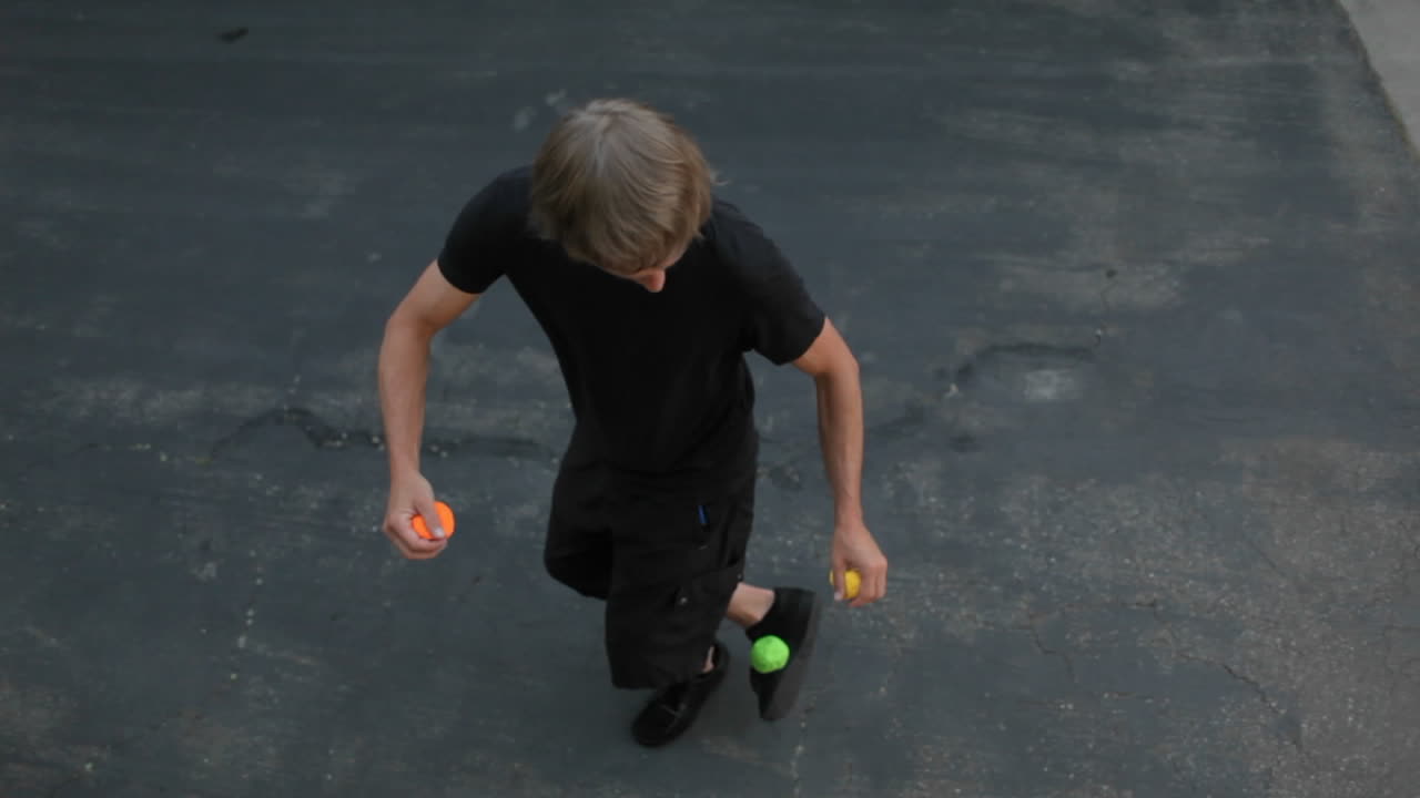 un hombre hace malabares en la calle con tres bolas de colores