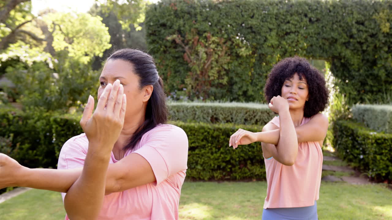 Exercising outdoors, women stretching arms in garden, enjoying fitness routine