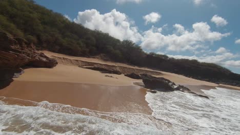 fpv drone disparó bajo sobre una playa iluminada por el sol y sobre las olas en la costa de hawaii, estados unidos