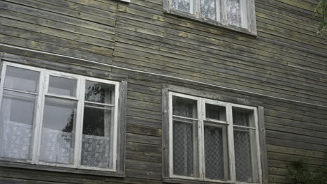 White-windows-with-curtains-on--house's-wooden-wall