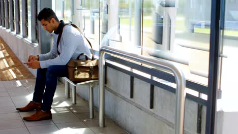 male commuter using mobile phone in waiting area 4k