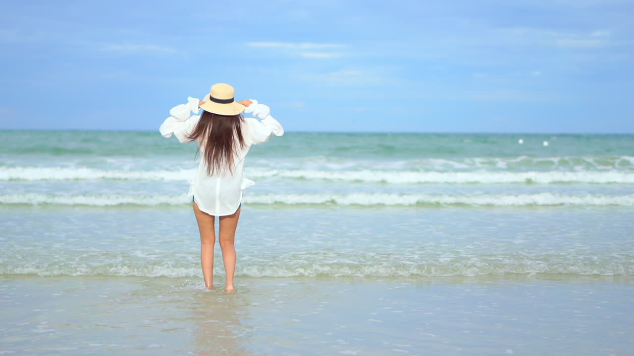 카메라를 등지고 건강하고 건강한 젊은 여성이 들어오는 파도에 부딪친다