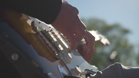 primer plano de manos masculinas tocando guitarra eléctrica, cámara lenta de alta calidad 4k, contra-jour