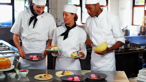 three chefs placing dessert plates on counter