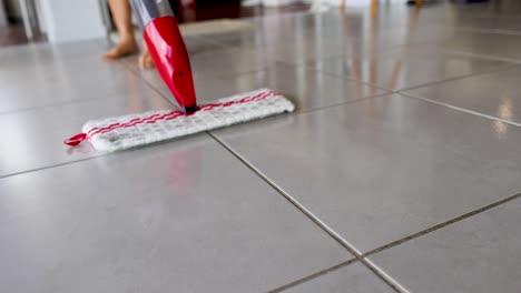 a red spray mop cleans a tiled floor, highlighting its efficiency and ease of use in a bright, modern setting
