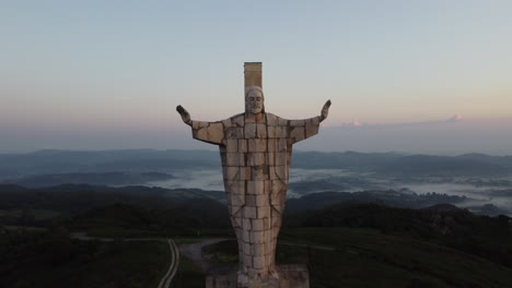 reveal of a religious statue made of concrete at the top of a mountain