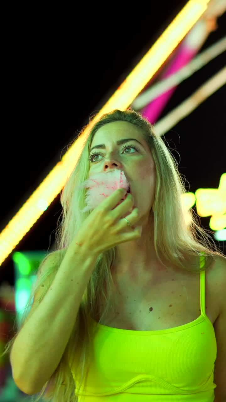 Woman eating cotton candy at a carnival