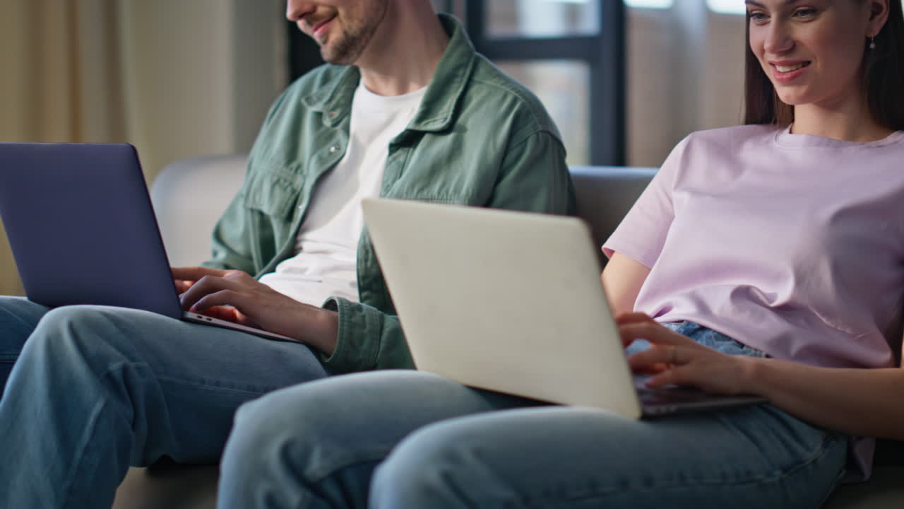 Working pair using laptops sitting domestic couch closeup. Freelancers couple